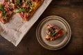 Piece of Italian Roman pizza lies on rustic ceramic plate, next to pizza on craft paper