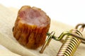 Piece of kabanosa meat lying on a pawl in a mousetrap, isolated on a white background.