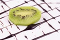 A piece of kiwi on a background of chocolate decorations