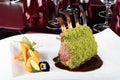 Piece of lamb rack with bone roasted with green herb, bread, sweet potatoes puree, baby vegetables Royalty Free Stock Photo