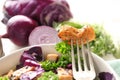 Piece of meat on fork over bowl with delicious salad, closeup Royalty Free Stock Photo