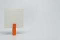 Piece of Memo paper clamped by orange wooden clip with white background and selective focus