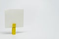 Piece of Memo paper clamped by yellow wooden clip with white bacckground and selective focus
