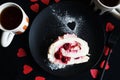 A piece of meringue roll on a black plate next to two cups of tea Royalty Free Stock Photo