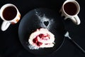A piece of meringue roll on a black plate next to two cups of tea Royalty Free Stock Photo