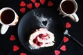 A piece of meringue roll on a black plate next to two cups of tea Royalty Free Stock Photo