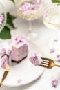 A piece of mousse cake, Delicious dessert blueberry tart with fresh berries with a bouquet of purple blooming lilacs, vertical Royalty Free Stock Photo