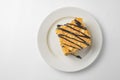 A piece of Napoleon cake with chocolate syrup served on a white plate over white background Royalty Free Stock Photo