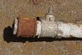 A piece of an old gray metal pipe with a broken faucet and a rusty brown nut Royalty Free Stock Photo