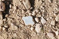 Piece of old tile on a sandy and rocky ground