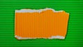 A piece of orange corrugated cardboard with torn edges on a green background. Bright modern background with copy space for text. Royalty Free Stock Photo