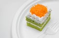 Piece of pandan cake with golden threads on top over plate