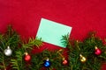 Piece of paper for Christmas wishes on a red background with branches of Christmas tree and Christmas balls Royalty Free Stock Photo