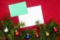 Piece of paper for Christmas wishes on a red background with branches of Christmas tree and Christmas balls Royalty Free Stock Photo