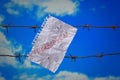 Piece of paper with forbidden text on barbed wire on sky background Royalty Free Stock Photo