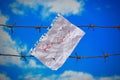 Piece of paper with get out text on barbed wire on sky background Royalty Free Stock Photo