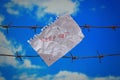 Piece of paper with keep out text on barbed wire on sky background Royalty Free Stock Photo