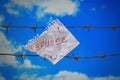 Piece of paper with refugee text on barbed wire on sky background Royalty Free Stock Photo