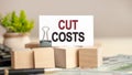 Piece of paper with the text: CUT COSTS, business and finance concept Royalty Free Stock Photo