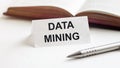 Piece of paper with text Data mining on the background of books, pens, on a white background Royalty Free Stock Photo