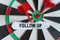 A piece of paper with the text is nailed to the target with a dart - FOLLOW UP