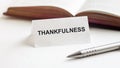 Piece of paper with text Thankfulness on the background of books, pens, on a white background