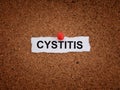 A piece of paper with the word Cystitis on it pinned to a cork board