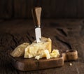 Piece of Parmesan cheese and cheese knife on the wooden board. Dark background Royalty Free Stock Photo