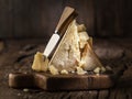 Piece of Parmesan cheese and cheese knife on the wooden board. Dark background Royalty Free Stock Photo