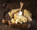 Piece of Parmesan cheese and cheese knife on the wooden board. Dark background Royalty Free Stock Photo