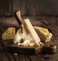 Piece of Parmesan cheese and cheese knife on the wooden board. Dark background Royalty Free Stock Photo