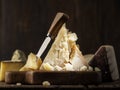 Piece of Parmesan cheese and cheese knife on the wooden board. Dark background Royalty Free Stock Photo