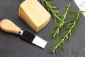 Piece of parmesan cheese, a knife and rosemary twigs on a black slab in a top view Royalty Free Stock Photo