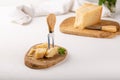 Piece of parmesan cheese on wooden board on white background. Parmigiano Reggiano, hard mature cheese