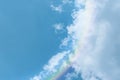 Piece of picturesque multicolored rainbow on the romantic sky. Clear afternoon day with white clouds. Background and wallpaper