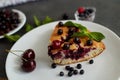 Piece of pie with blueberries, rasberry,cherries and mint for dessert on a white plate, napkin. Pieces of delicious homemade cake. Royalty Free Stock Photo