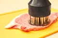 Piece of pork and meat tenderizer on cutting board