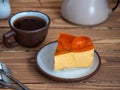 A piece of pumpkin cake and mocha tea in a brown ceramic mug removed from close distortion