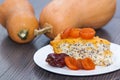 Piece of pumpkin homemade cheesecake with dried apricots, poppy, orange, date fruit on the wooden table. Thanksgiving Day. Royalty Free Stock Photo