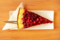 Piece of raspberry pie on a wooden table in warm summer sunlight