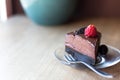 A piece of raw avocado chocolate cake with a bright raspberry and oreo cookie on top.