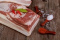 Piece of raw pork belly with salt and red paprika on wooden table Royalty Free Stock Photo