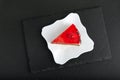 Piece of red fruit cake on white plate. Top view of cake on black background Royalty Free Stock Photo
