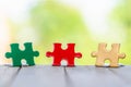 Piece of Red green and gold jigsaw puzzle On the old wood And green background. teamwork concept. symbol of association and Royalty Free Stock Photo