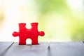 Piece of Red  jigsaw puzzle On the old wood And green background. teamwork concept.  symbol of association and connection. Royalty Free Stock Photo