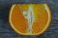 A piece of ripe orange lies on a gray table