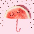 Piece of ripe watermelon in the form of an umbrella with black seeds against pink background Royalty Free Stock Photo