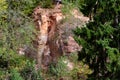 Piece of rock red, yellow, brown, white shades, large cliff surrounded by green and yellowing vegetation Royalty Free Stock Photo