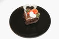 piece of romantic chocolate cake on black plate. Small baked cake decorated for Saint Valentines Day with love and heart mastic