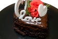 piece of romantic chocolate cake on black plate. Small baked cake decorated for Saint Valentines Day with love and heart mastic